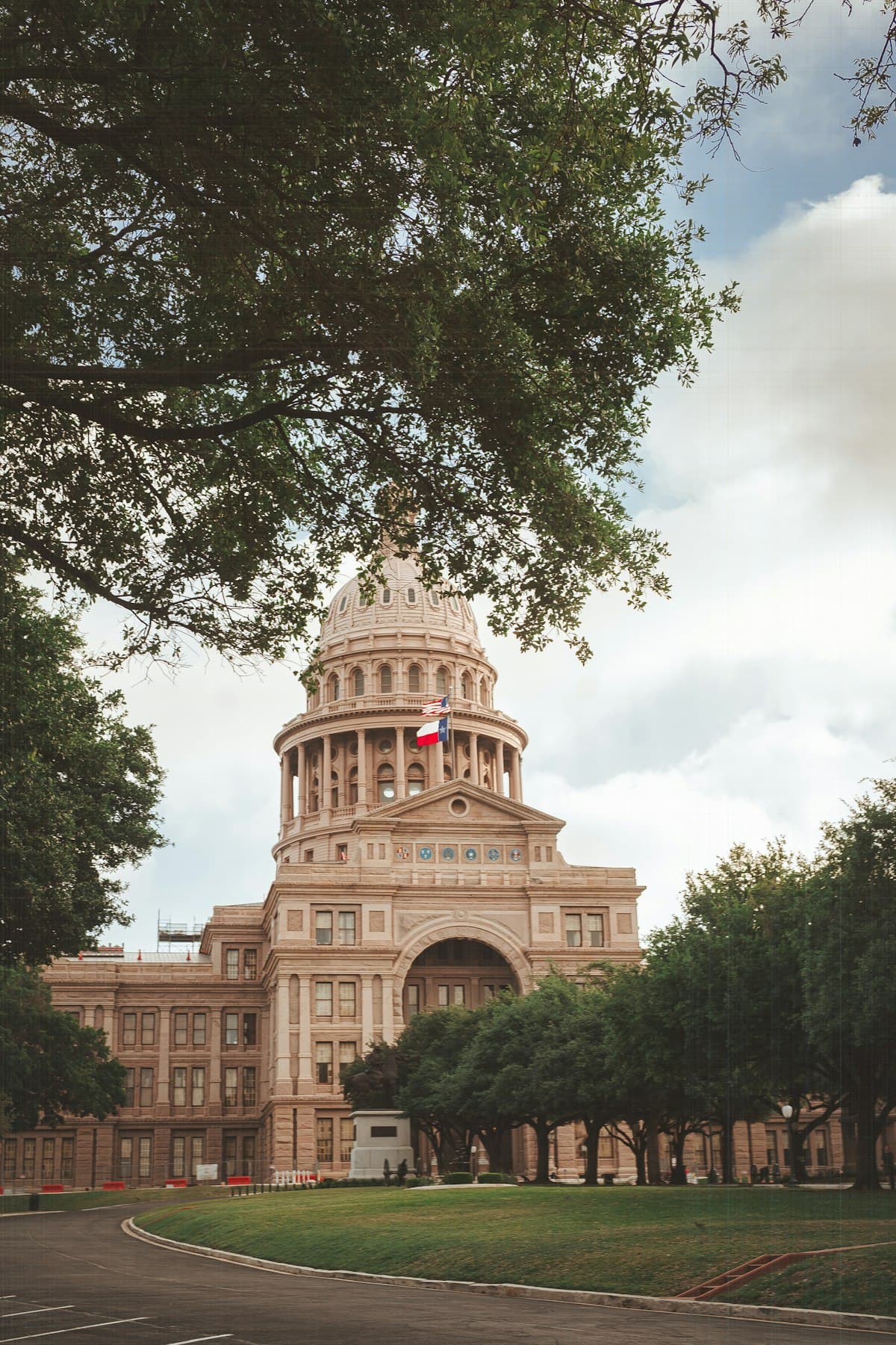 Texas State Capitol building in Austin framed by oak trees