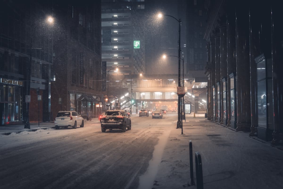 Chicago street during winter snowstorm at night with cars and city lights