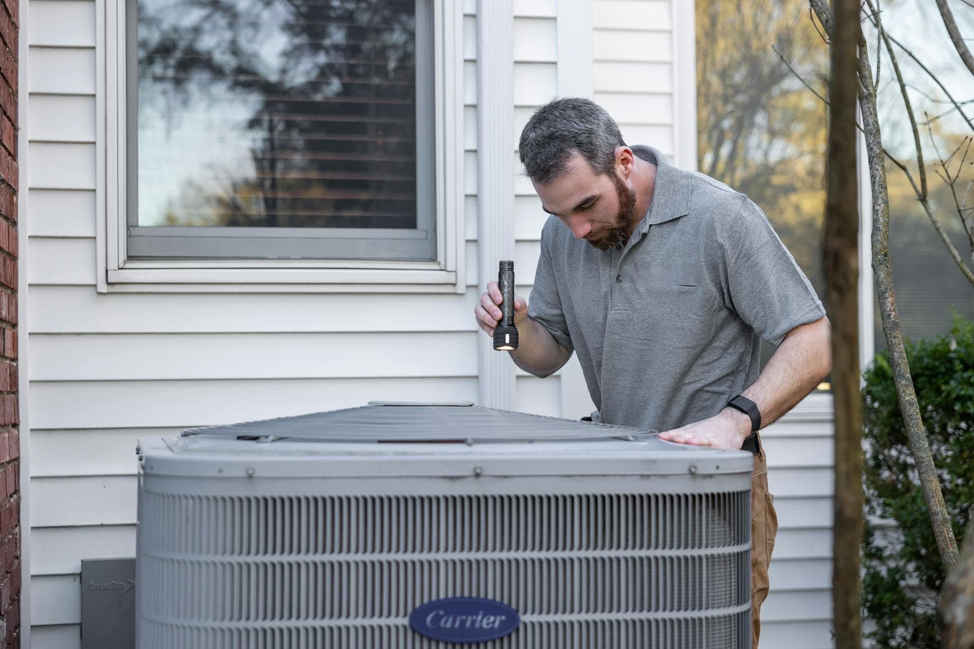HVAC technician inspecting outdoor Carrier air conditioning unit