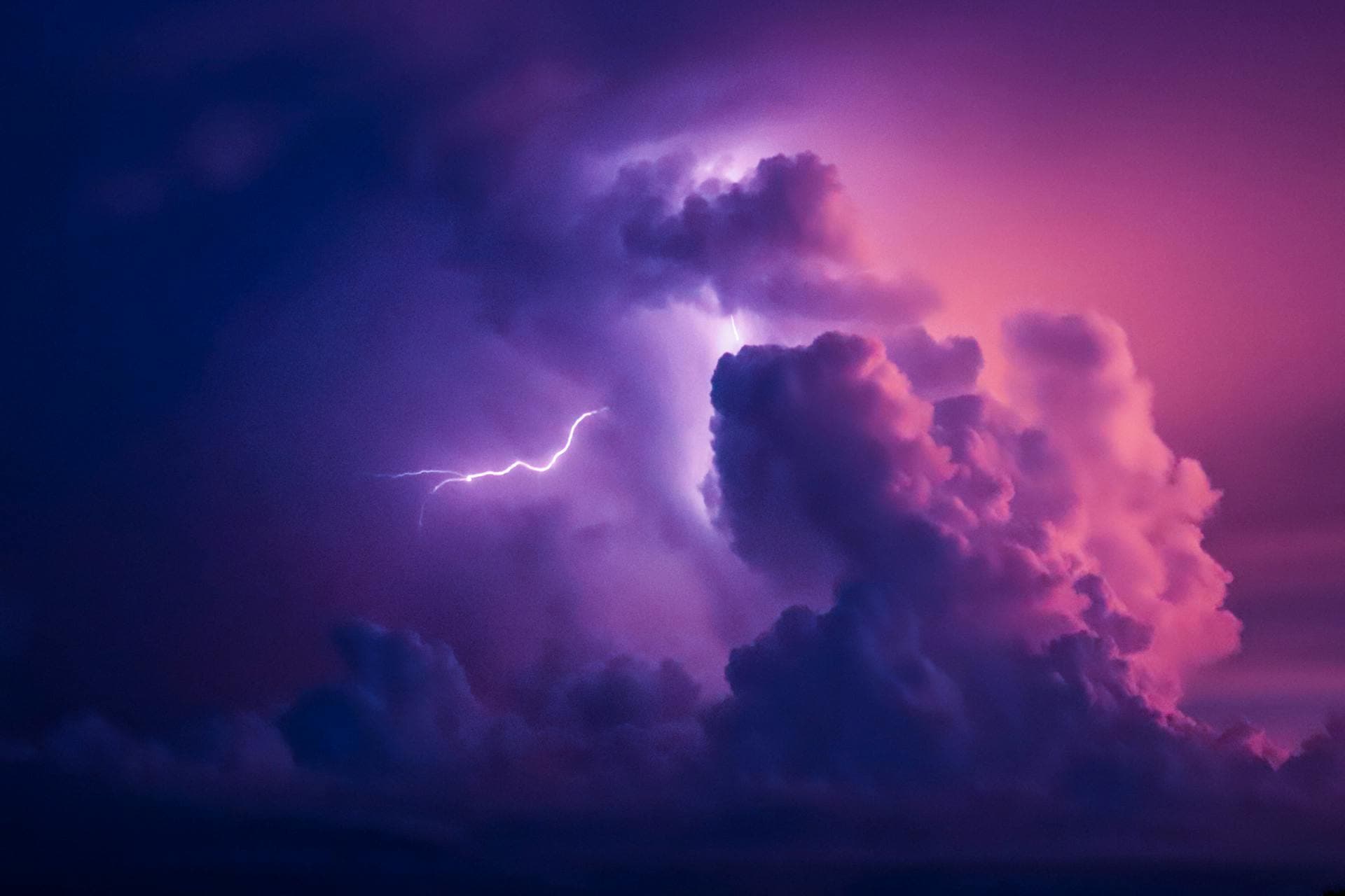 Dramatic lightning strike illuminating purple monsoon clouds in the night sky