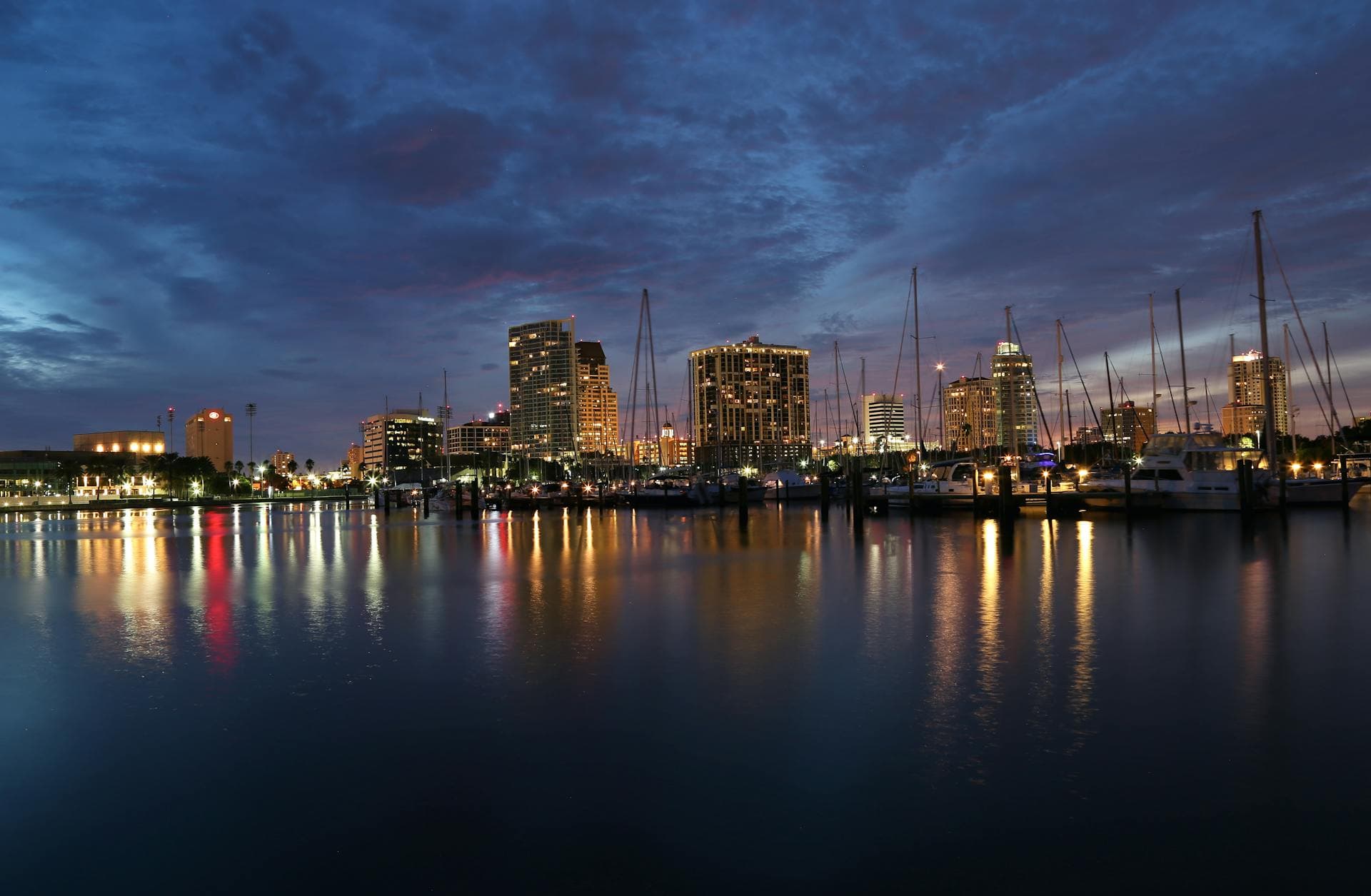St. Petersburg marina at dusk with downtown skyline and sailboats reflected in water