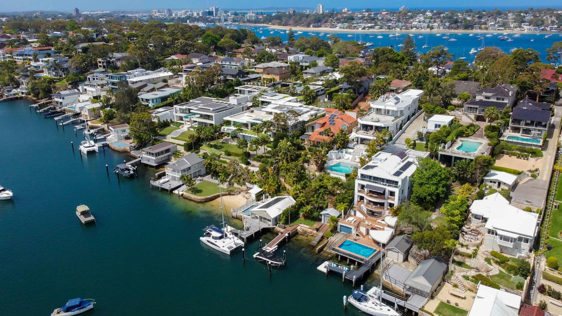 Aerial view of coastal waterfront homes with boats and pools in Florida