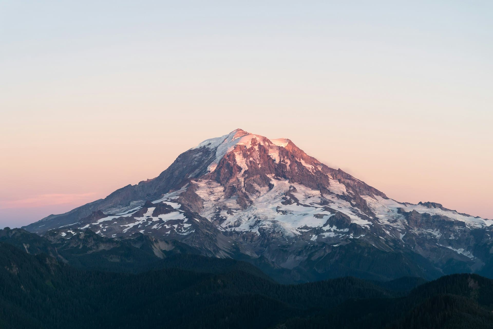 Mount Rainier at sunset with snow-covered peak glowing pink and blue