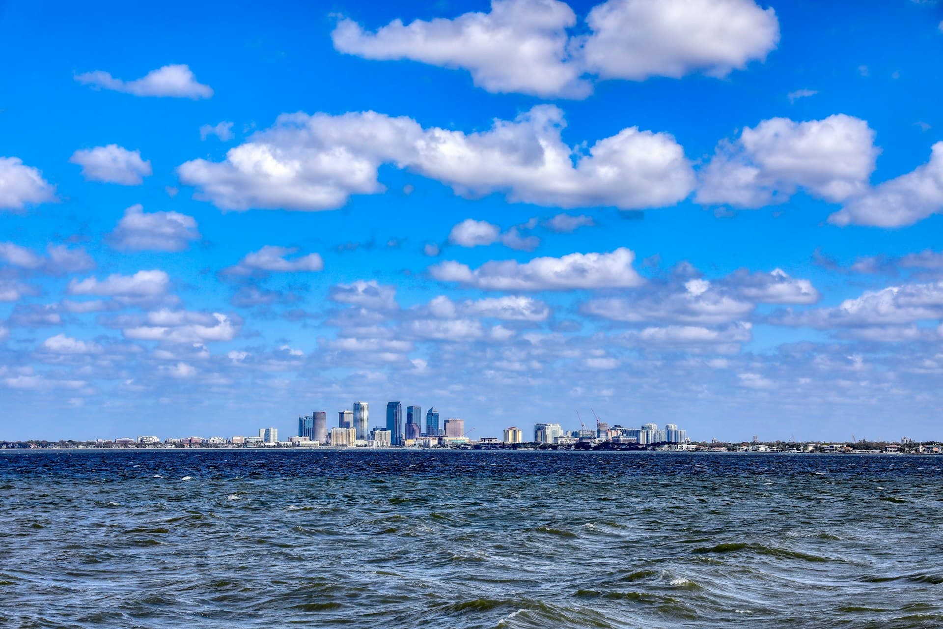 Tampa skyline viewed from across Tampa Bay under blue sky with clouds